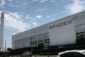 SpaceX building in Hawthorne, California with on its left a Falcon rocket.